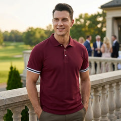Man wearing wine red polo shirt with striped cuffs on outdoor terrace at sunset