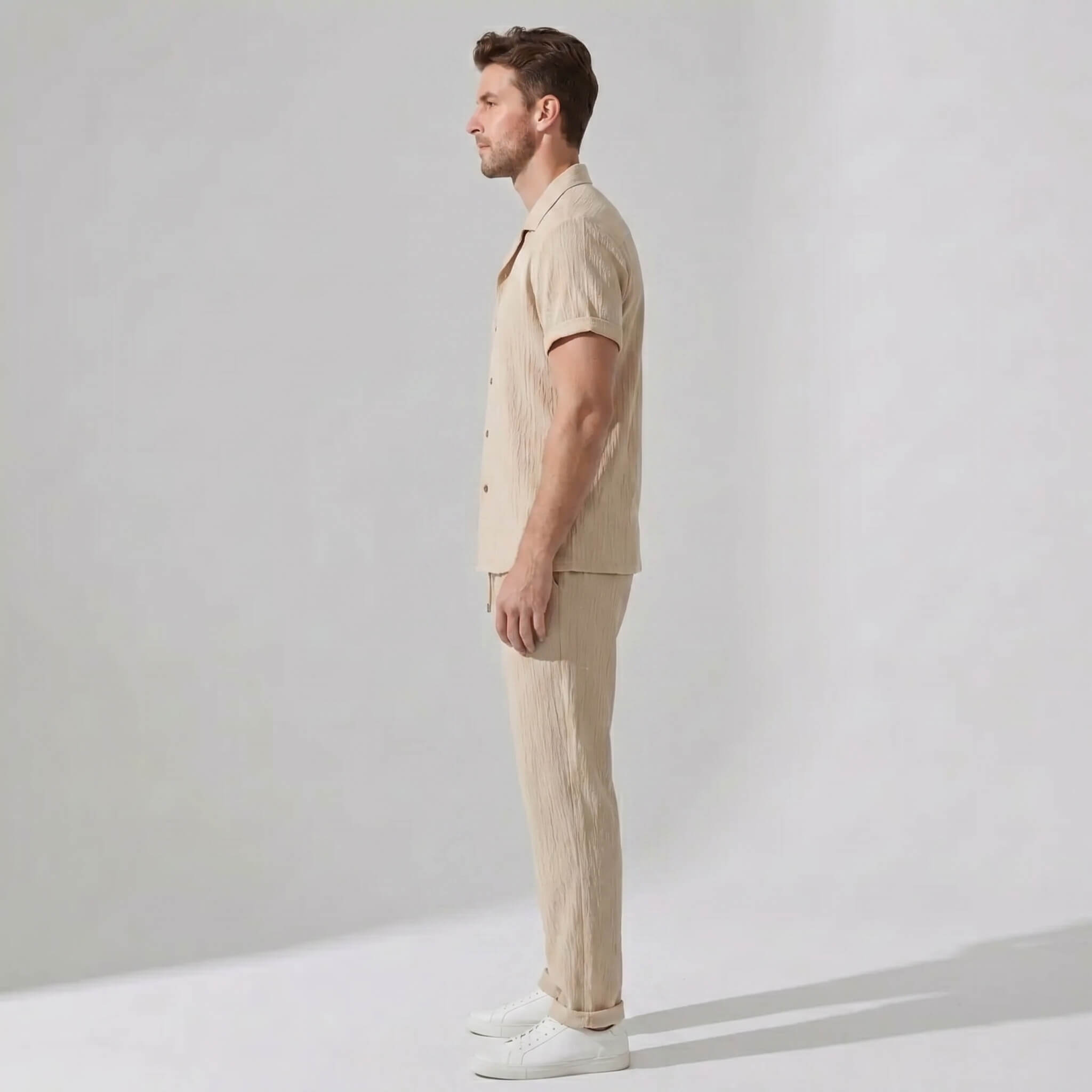 Side view of man in tan crinkled textured button up shirt and straight leg pants
