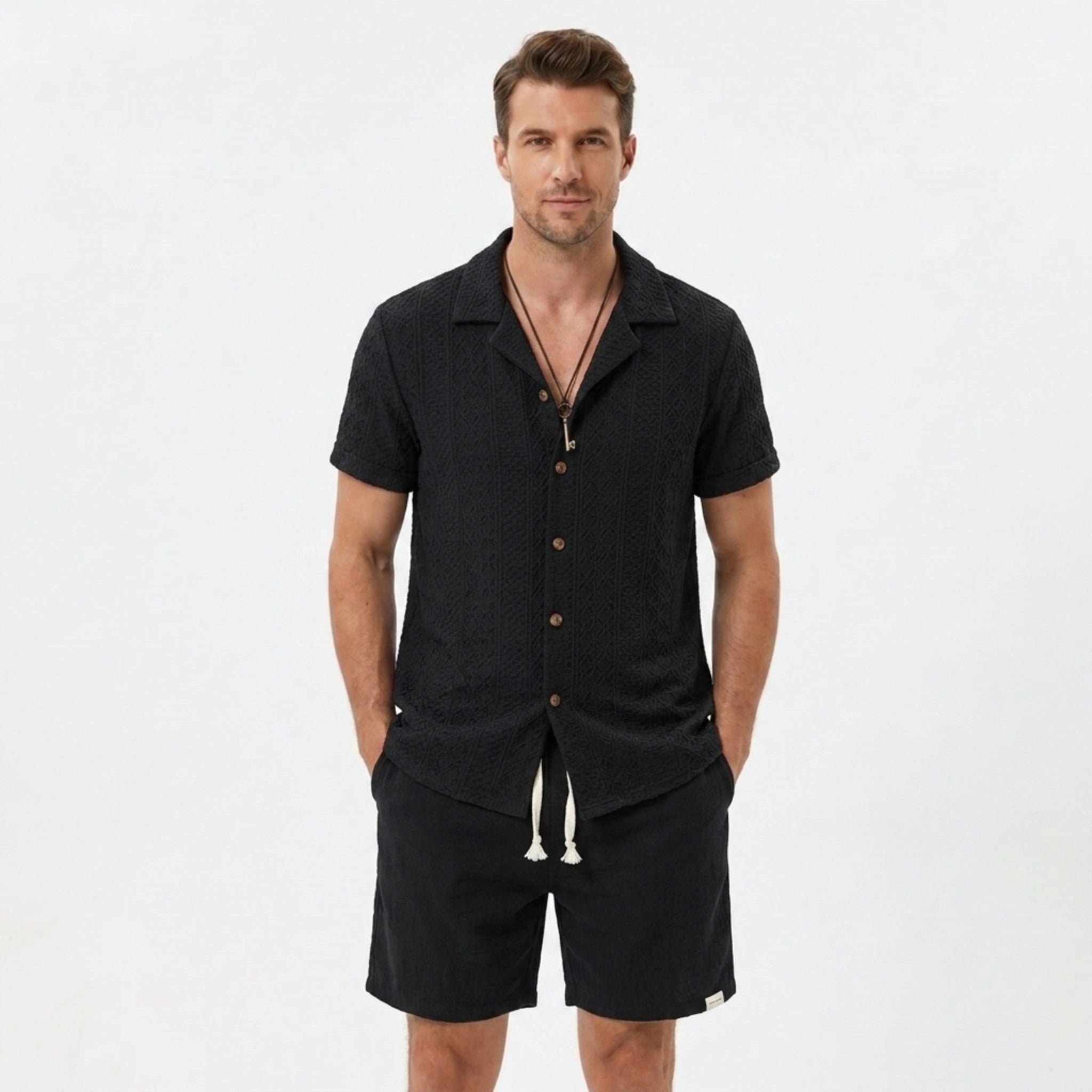 Back view of man wearing tan floral checkerboard jacquard Cuban shirt and linen drawstring shorts