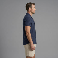 Side view of man in tan geometric jacquard shirt and crinkle shorts on plain background