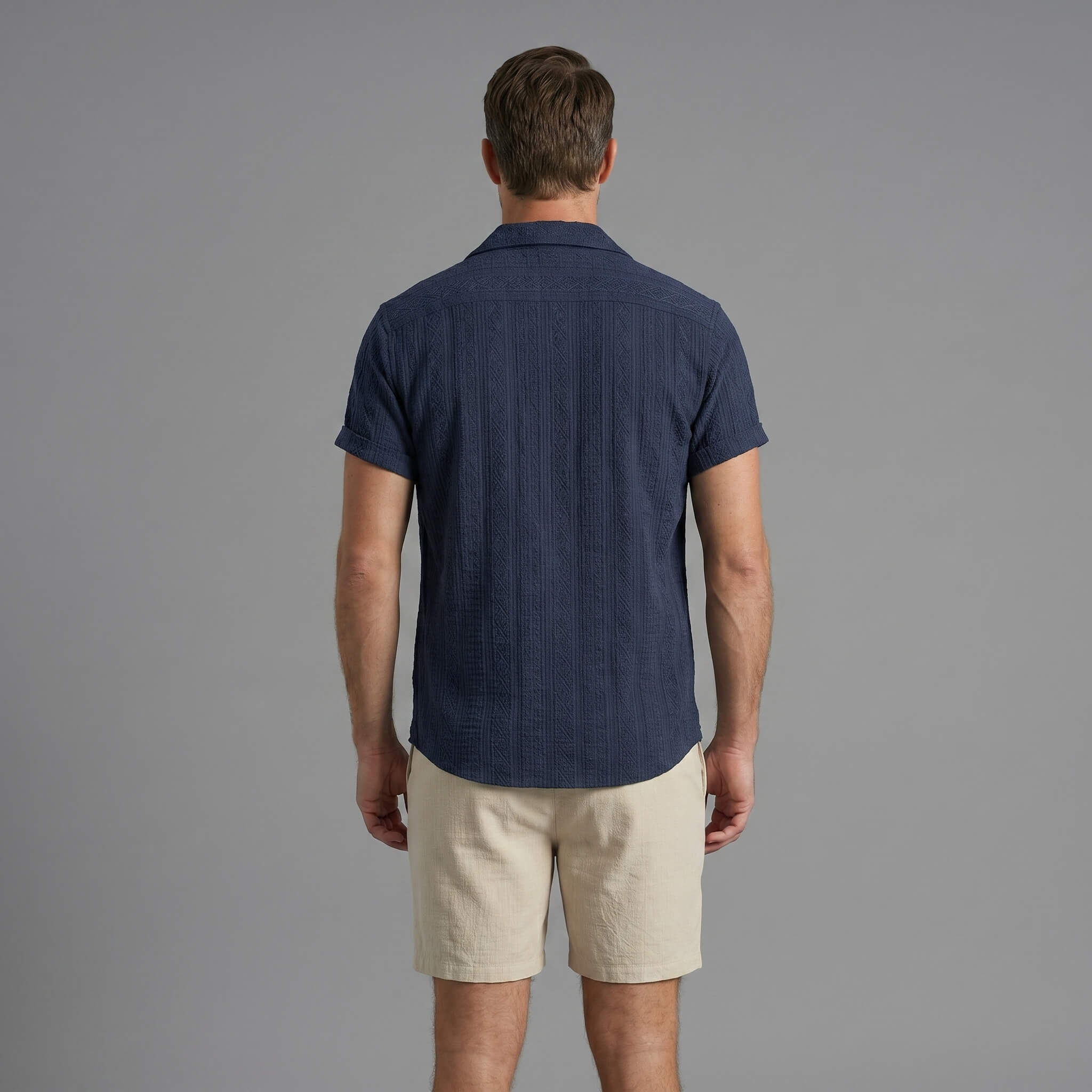 Three quarter view of man in tan geometric jacquard shirt and crinkle shorts