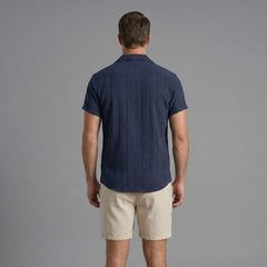 Three quarter view of man in tan geometric jacquard shirt and crinkle shorts