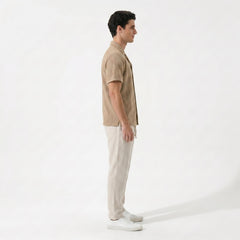Back view of man in tan geometric jacquard shirt and linen pants in outdoor lifestyle scene