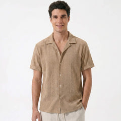 Three quarter view of man in tan geometric jacquard shirt and linen pants in outdoor setting