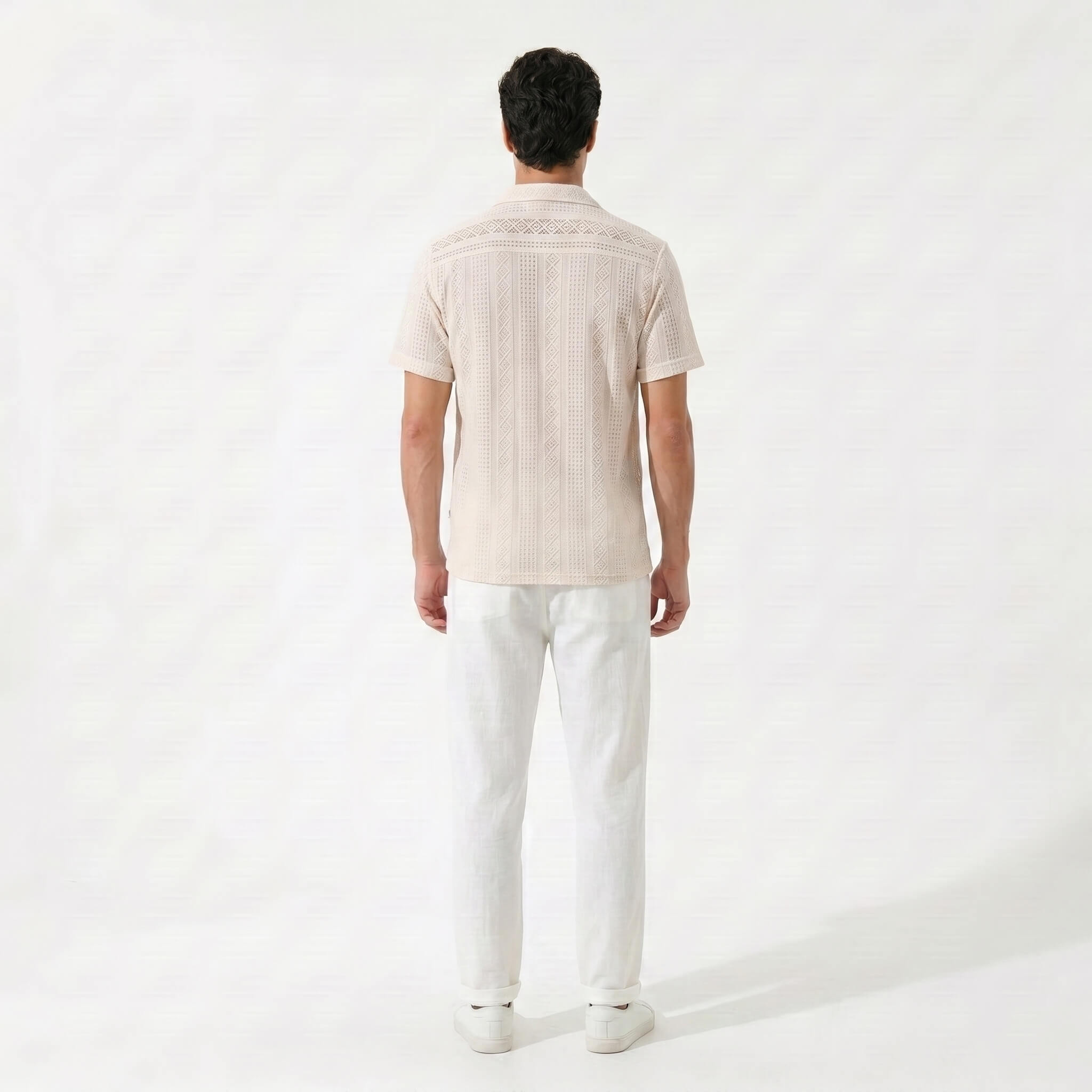 Side view of man in tan geometric jacquard button up shirt and straight leg linen pants