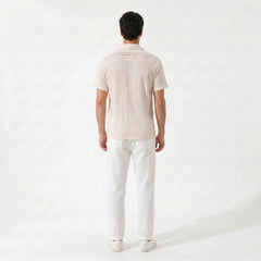 Side view of man in tan geometric jacquard button up shirt and straight leg linen pants