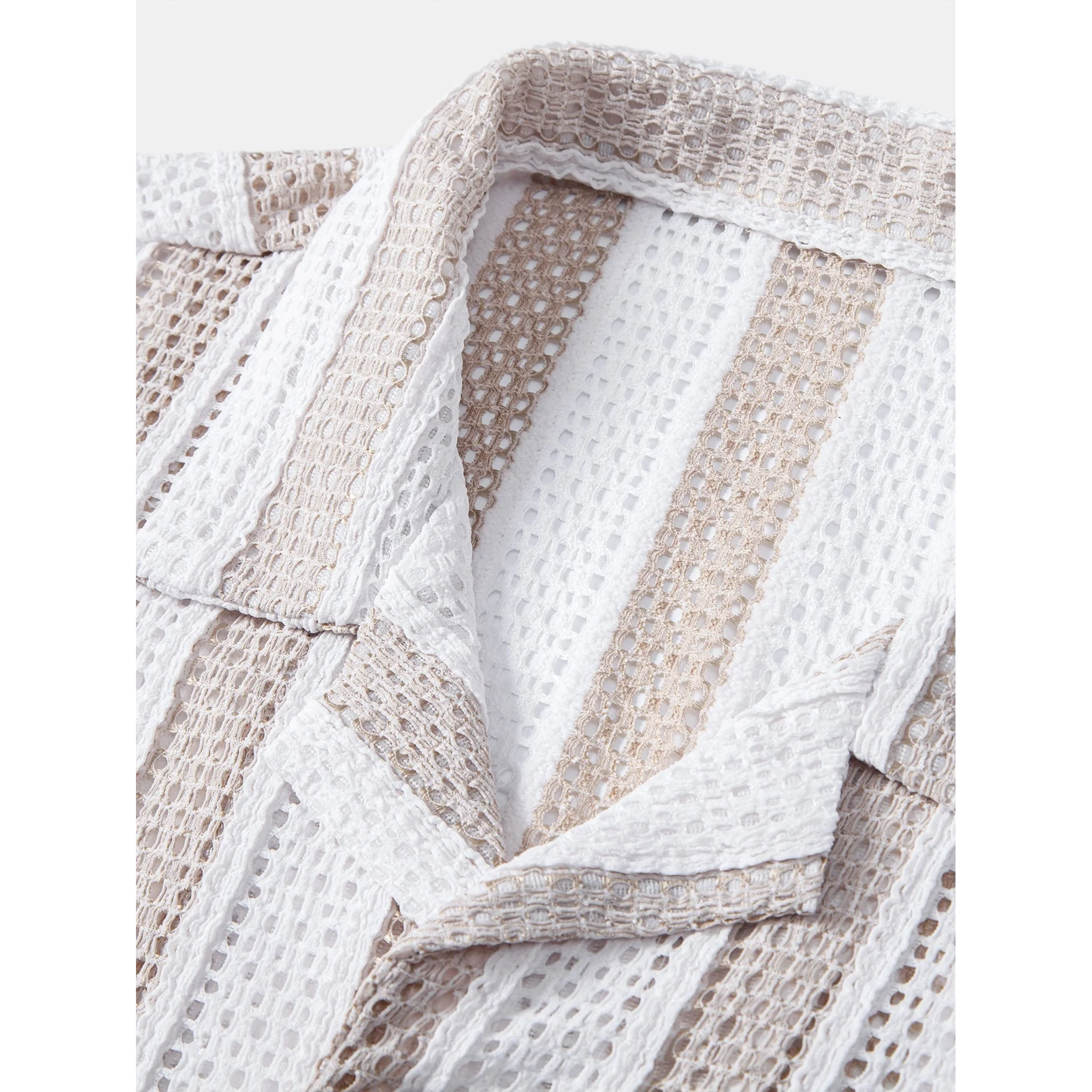 Three quarter view of man wearing tan mesh Cuban shirt and beige straight leg linen pants