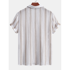 Man in tan open weave striped shirt and linen pants with hands at sides on plain background