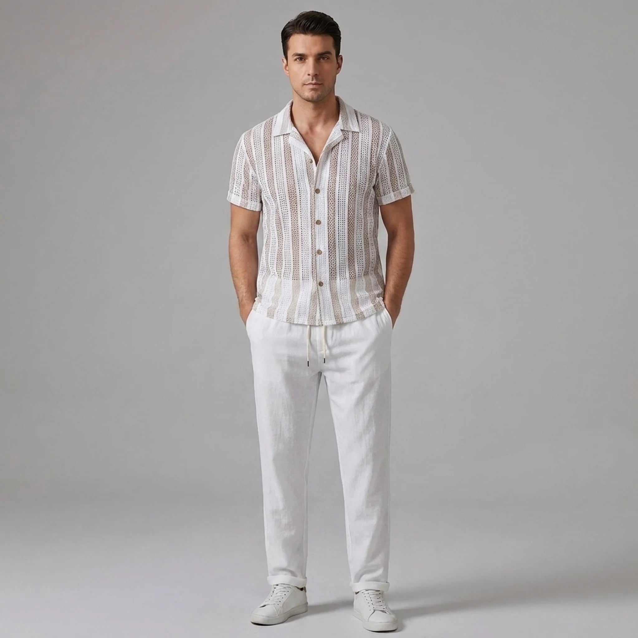 Man wearing a tan striped mesh Cuban shirt and beige linen pants on a light gray background