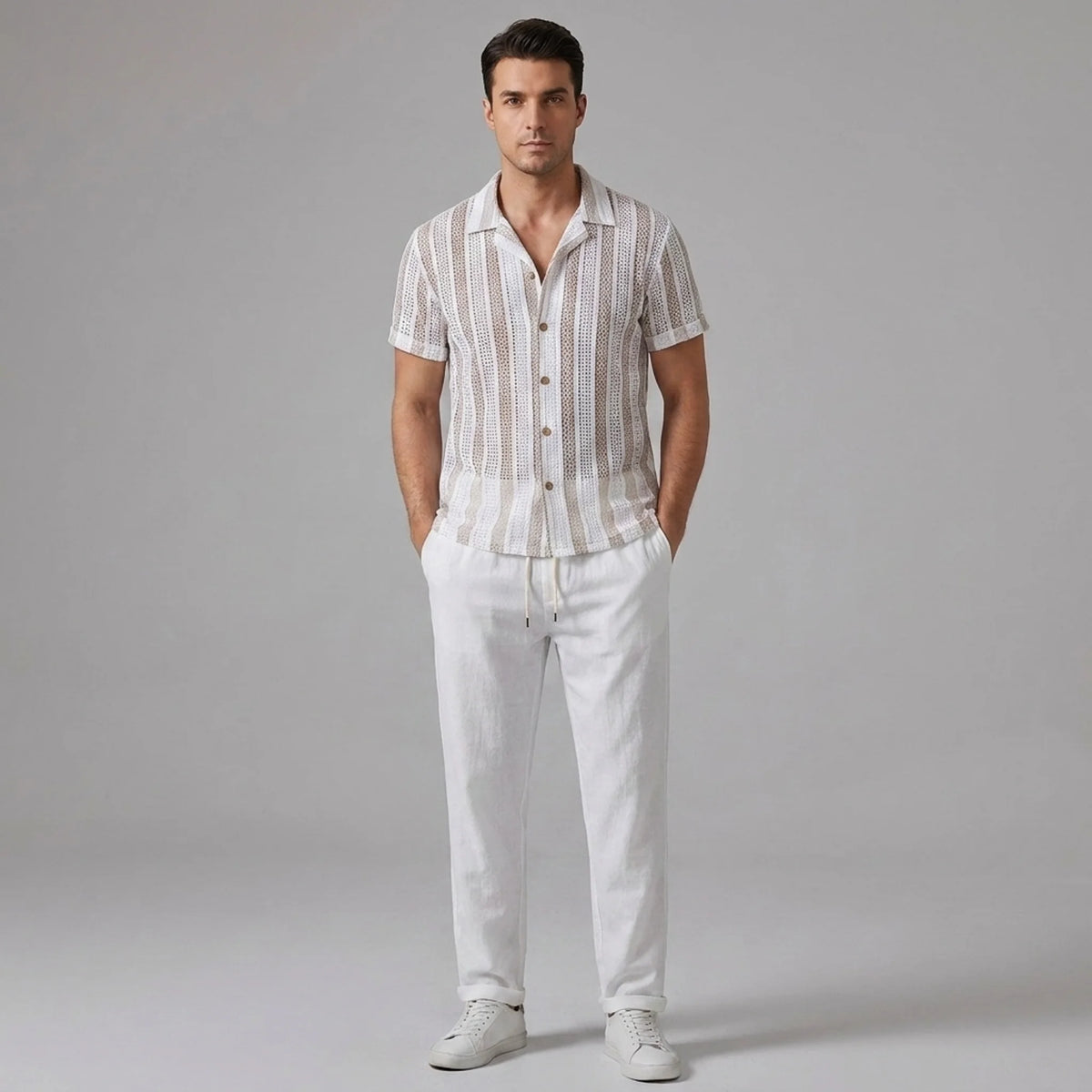 Man wearing a tan striped mesh Cuban shirt and beige linen pants on a light gray background