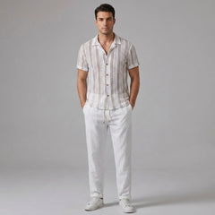 Man wearing a tan striped mesh Cuban shirt and beige linen pants on a light gray background