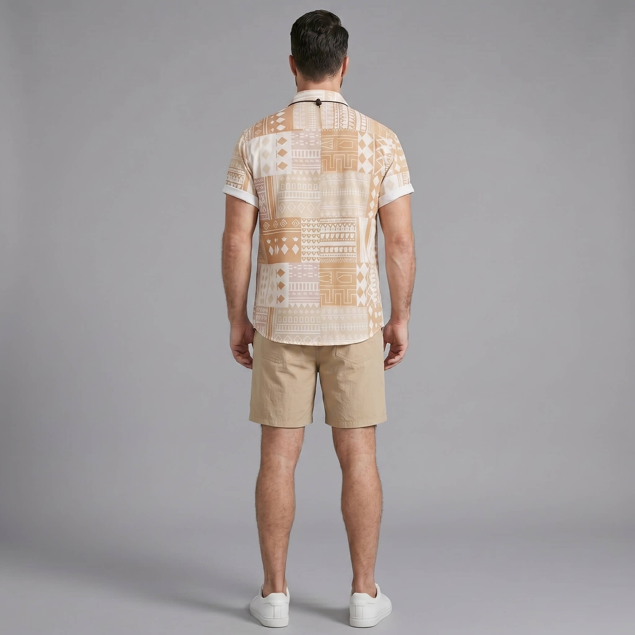 Back view of man wearing tan tribal geometric patchwork shirt and swim shorts