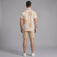 Back view of man wearing tan tribal geometric patchwork shirt and swim shorts