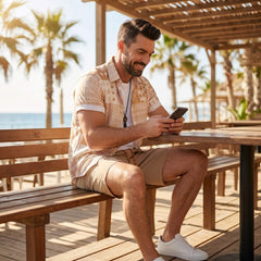 Man wearing tan tribal geometric patchwork shirt and swim shorts in outdoor lifestyle setting