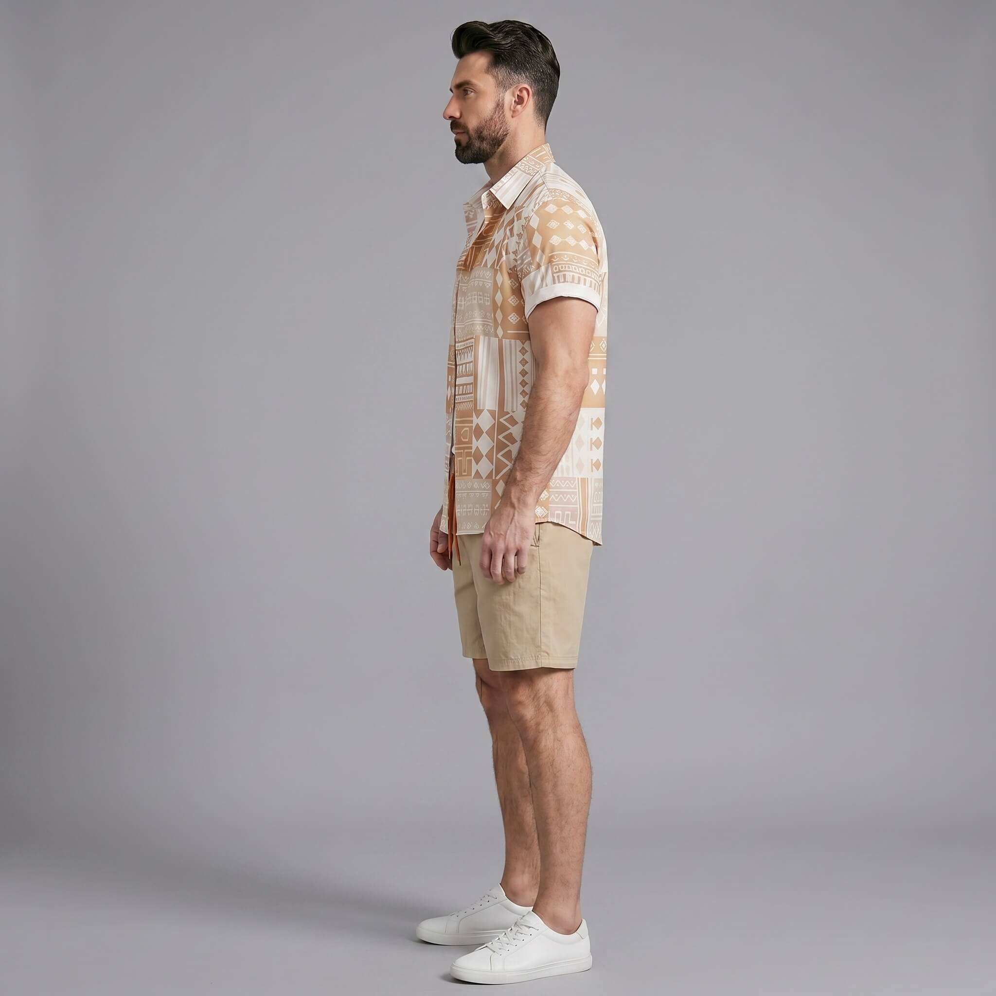 Side view of man in tan tribal geometric patchwork button up shirt and swim shorts
