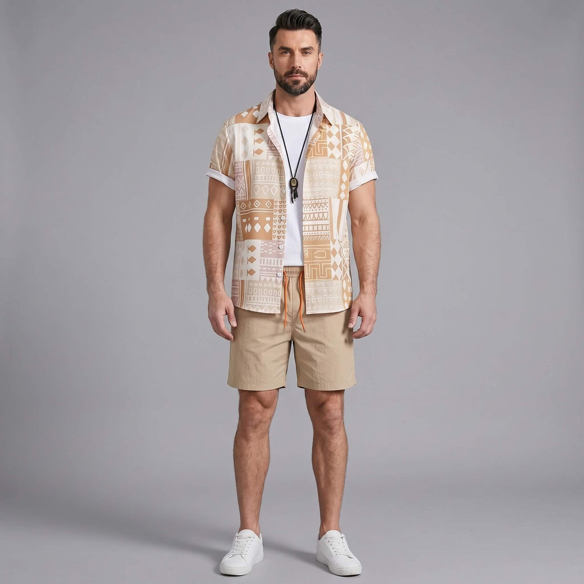 Three quarter view of man in tan tribal geometric patchwork shirt and swim shorts on plain background