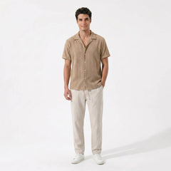 Man in tan geometric jacquard shirt and linen pants walking in sunny outdoor summer scene