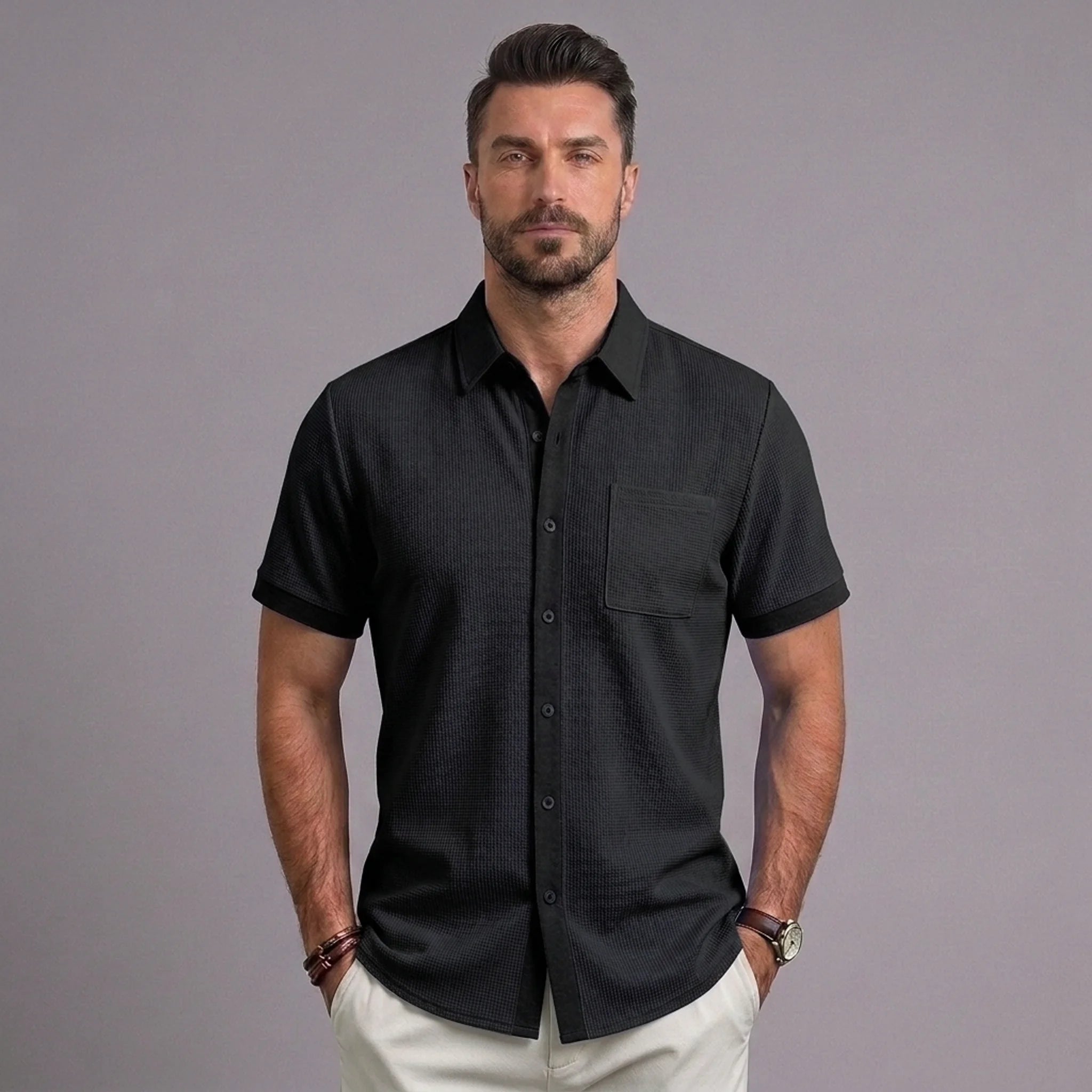 Man wearing black waffle knit short sleeve button-up shirt with chest pocket and white chinos