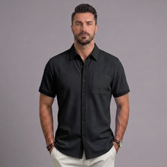 Man wearing black waffle knit short sleeve button-up shirt with chest pocket and white chinos