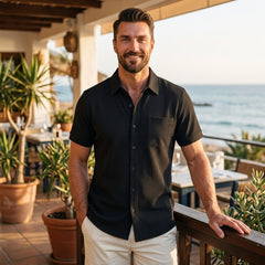 Man wearing black waffle knit short sleeve shirt at a seaside restaurant terrace