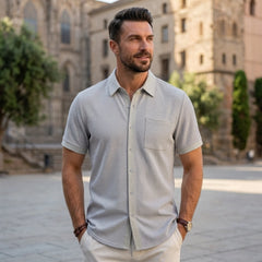 Man wearing light gray waffle knit short sleeve shirt outdoors near stone building