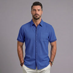 Man wearing royal blue waffle knit short sleeve casual shirt with chest pocket and white trousers