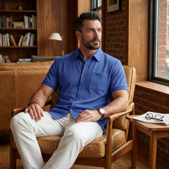 Man in royal blue waffle knit shirt seated in leather chair in warm library setting