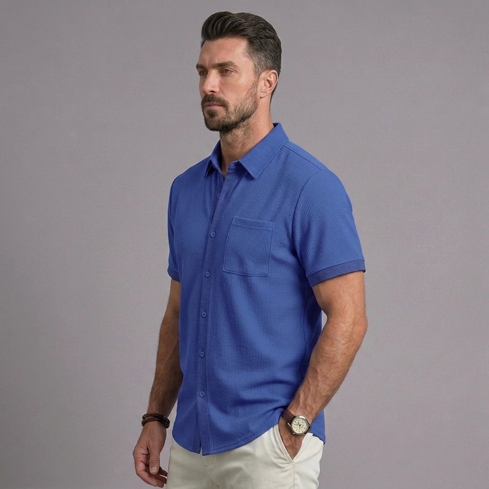 Man wearing royal blue waffle knit short sleeve shirt with chest pocket and white chinos, side view