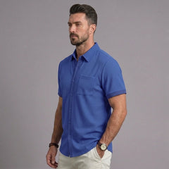 Man wearing royal blue waffle knit short sleeve shirt with chest pocket and white chinos, side view