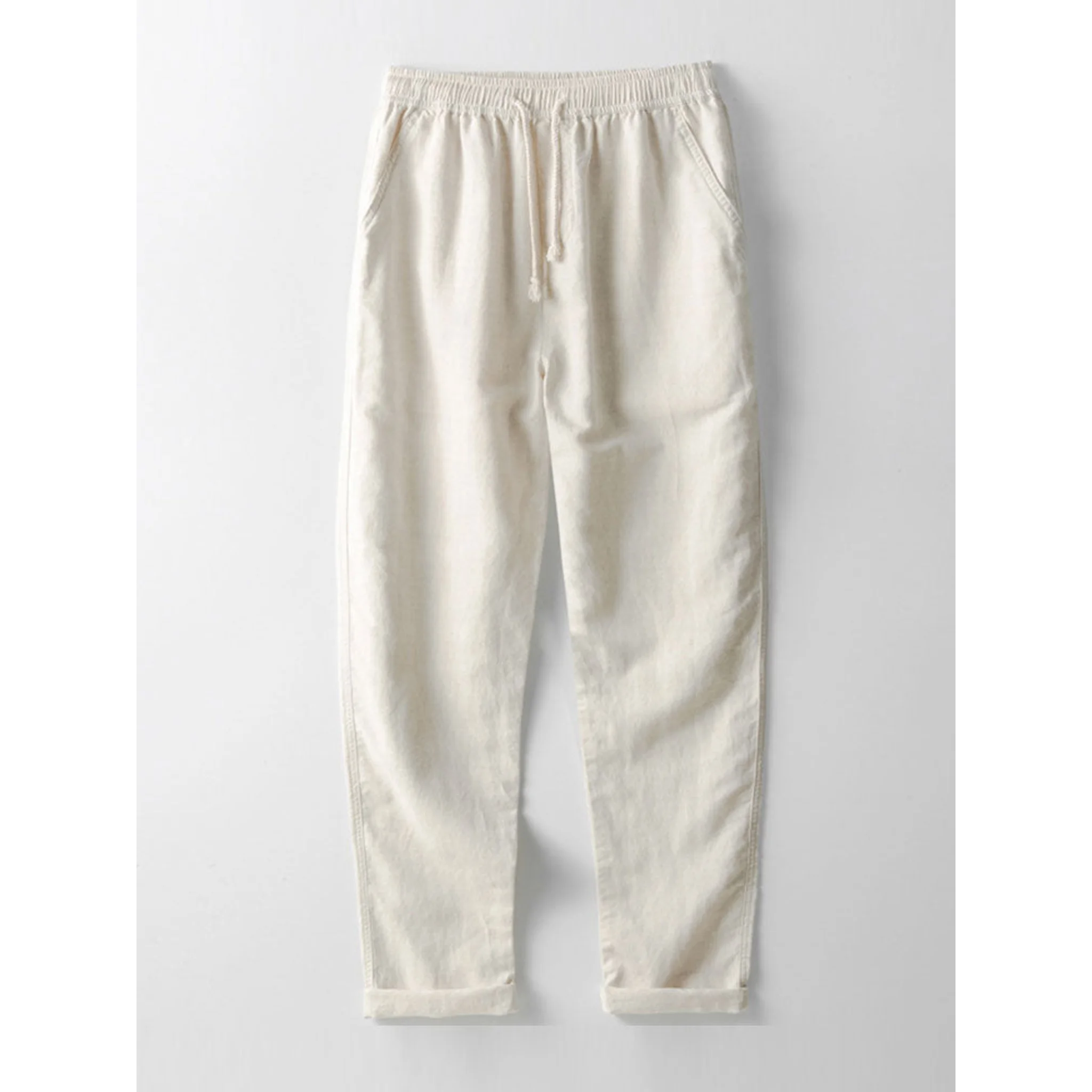 Side view of man in white and beige geometry textured Cuban shirt and linen pants on plain background
