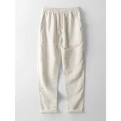 Side view of man in white and beige geometry textured Cuban shirt and linen pants on plain background