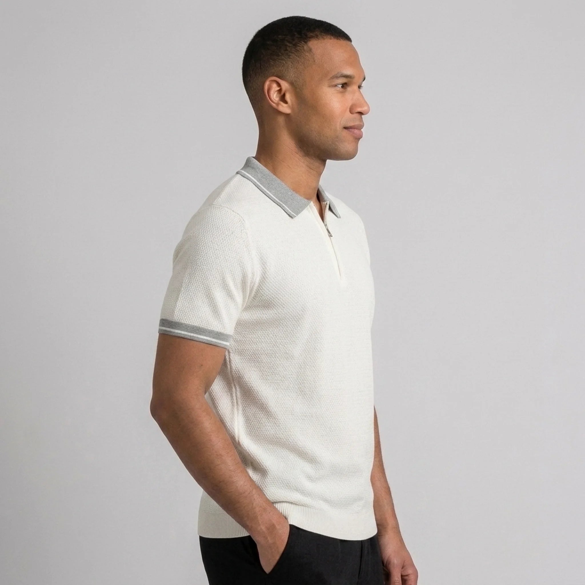 Side view of man in white color block knit polo shirt with lapel collar