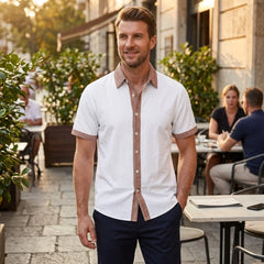 MannerCo white linen blend short sleeve shirt with contrast terracotta trim, worn by man at outdoor café