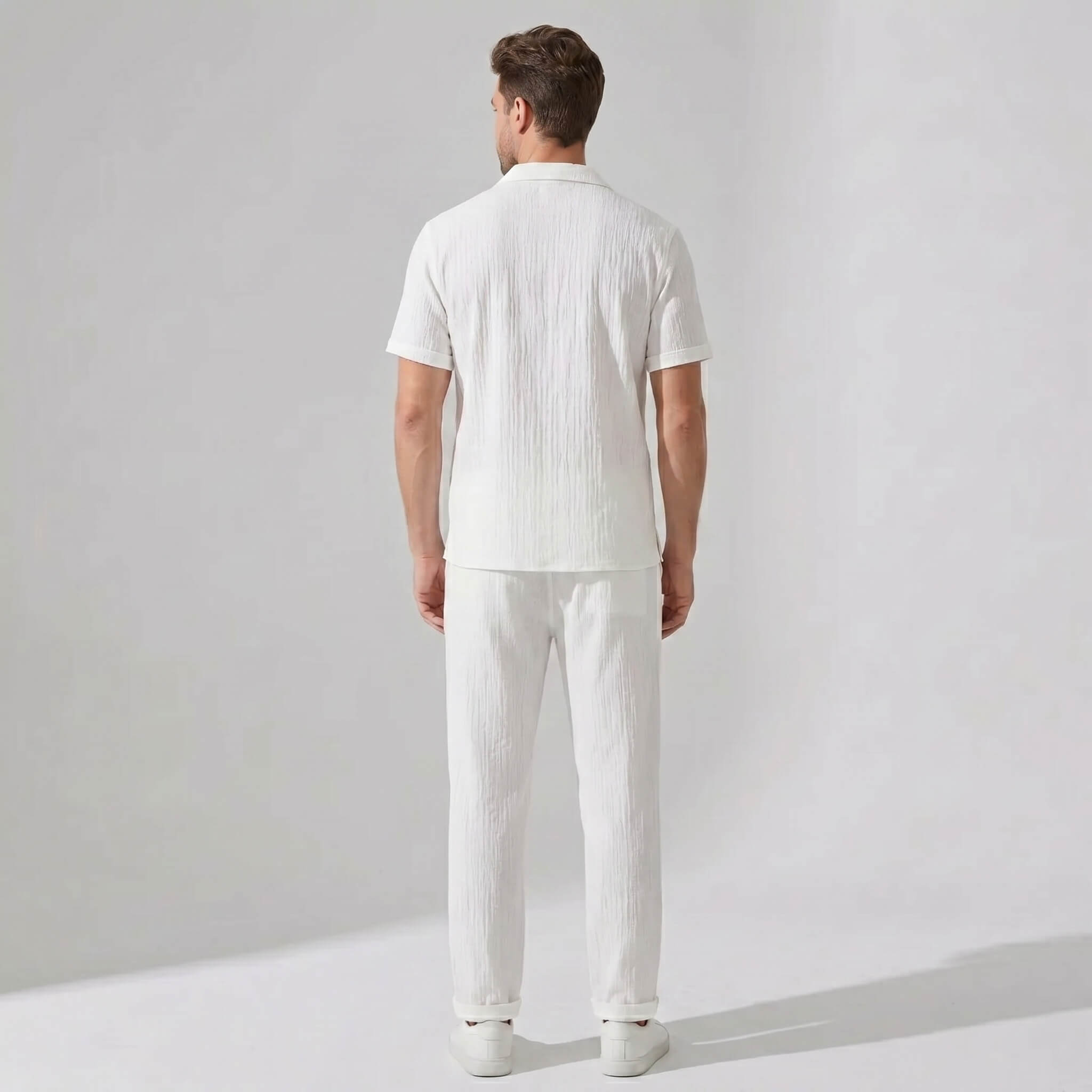 Back view of man wearing white crinkled textured button up shirt and straight leg pants