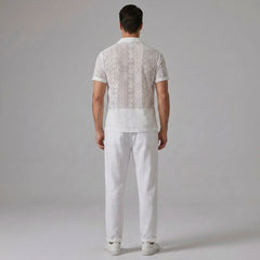Three quarter view of man in white geometry textured Cuban shirt and linen pants on plain background
