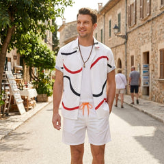 Man wearing white line print button up shirt and swim shorts in outdoor lifestyle setting