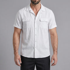 Three quarter view of man in white linen Cuban collar shirt and slim fit tapered trousers