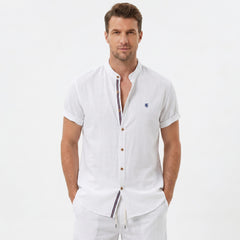 Three quarter view of man in white linen look stand collar shirt and crinkle drawstring shorts