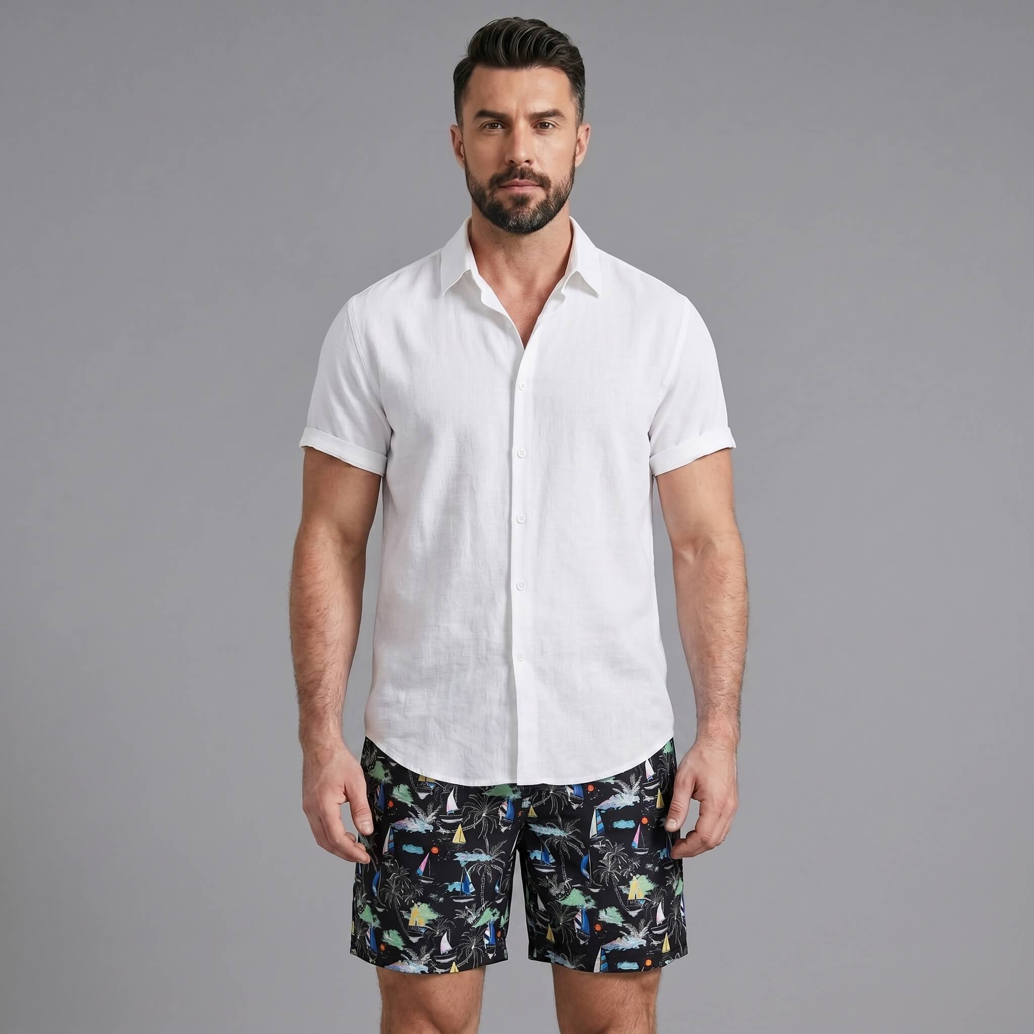 Man wearing a white linen rayon button up shirt and black palm tree print swim shorts front view on plain background