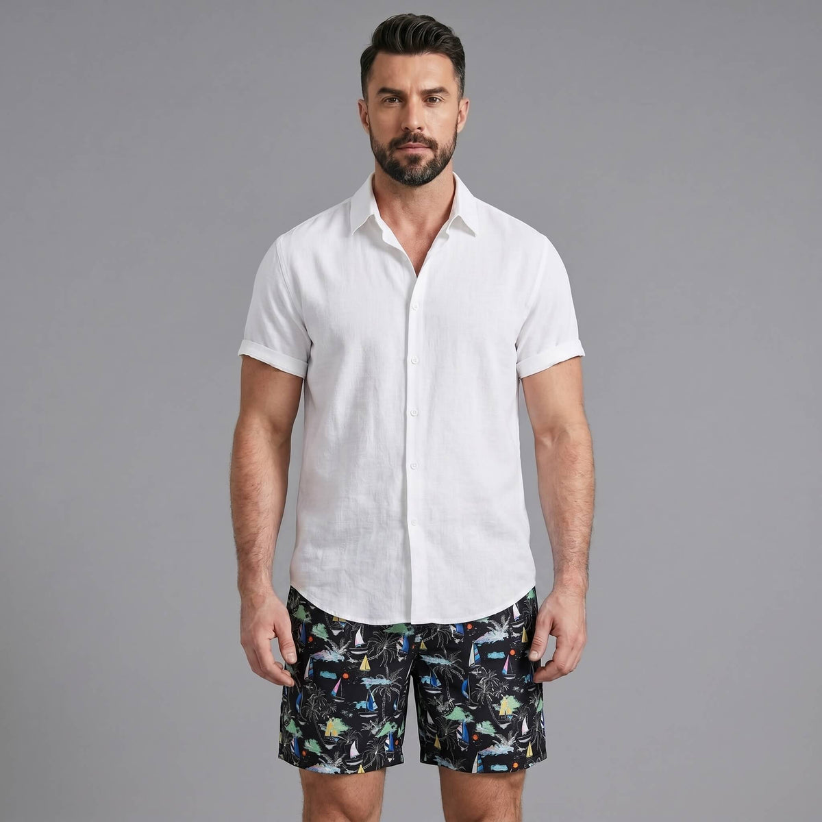 Man wearing a white linen rayon button up shirt and black palm tree print swim shorts front view on plain background
