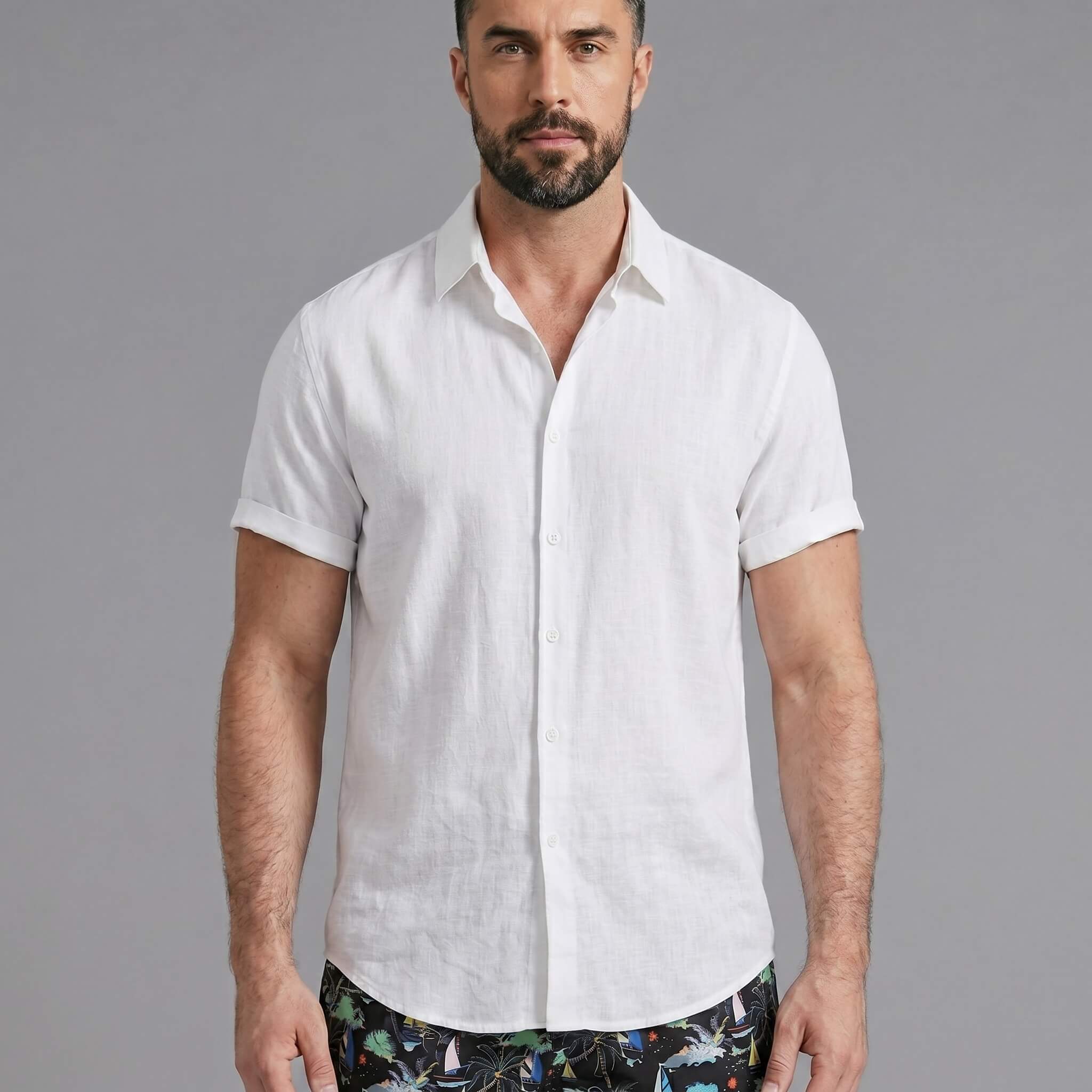 Three quarter view of man in white linen rayon shirt and black palm tree print swim shorts