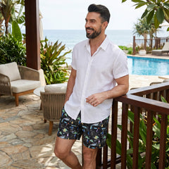 Man in white linen rayon shirt and white palm tree swim shorts in sunny beach outdoor setting