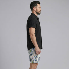 Man wearing a white linen rayon button up shirt and white palm tree print swim shorts front view