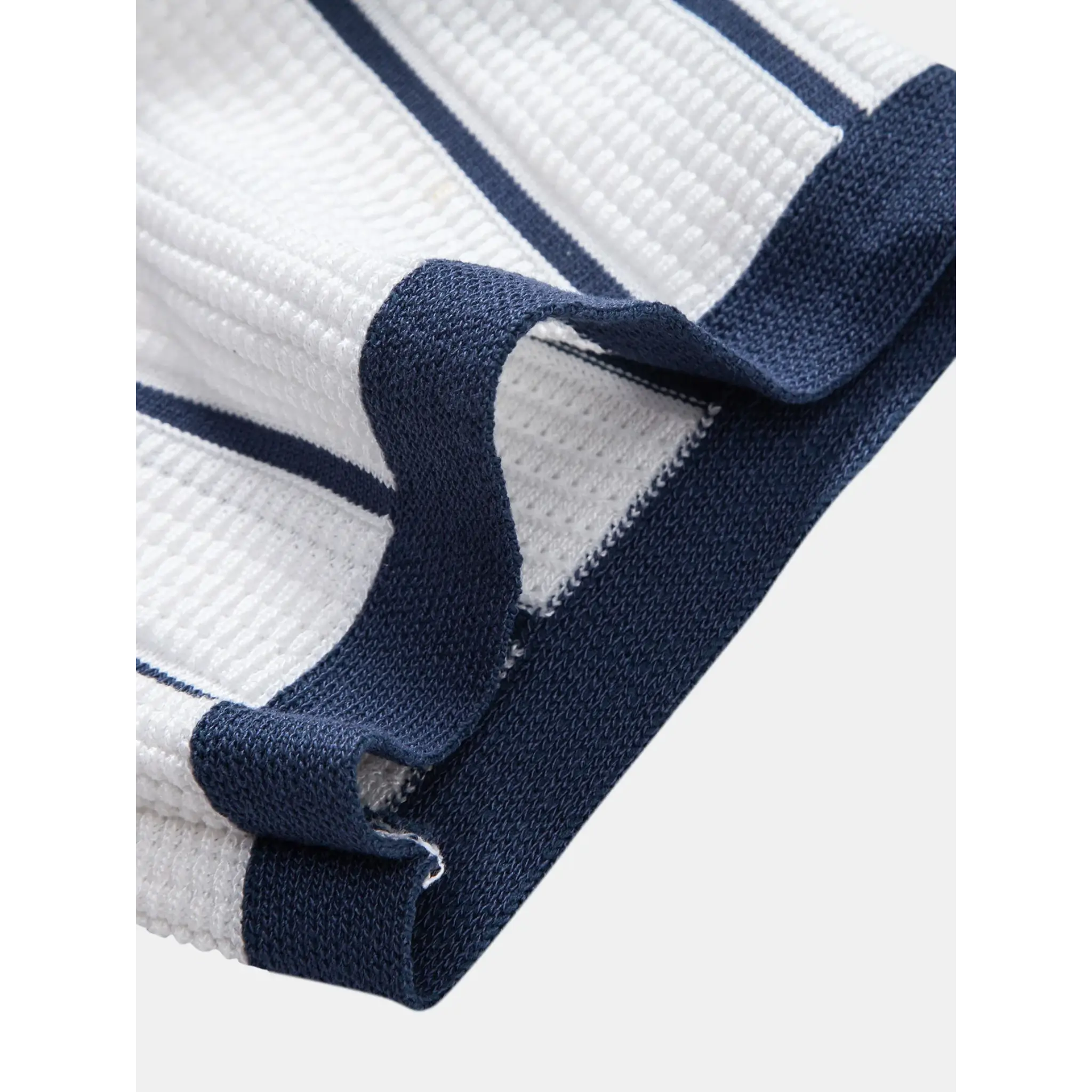 Full length view of man wearing white and navy striped knit shirt and straight leg linen pants on white background