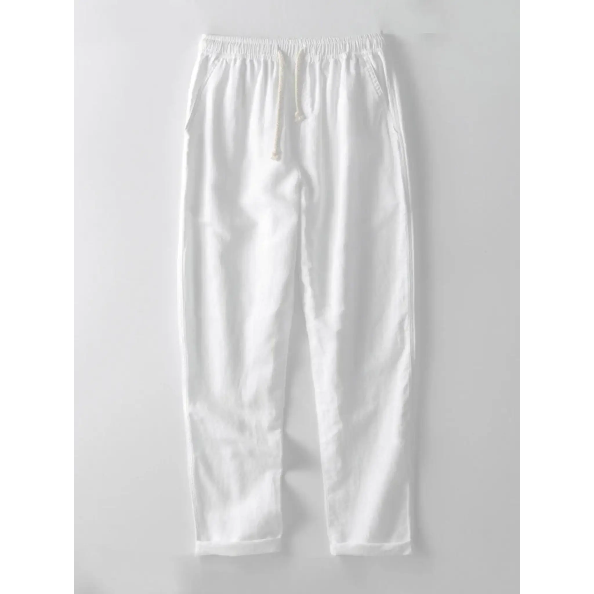 Three quarter view of man wearing white and navy striped knit shirt and straight leg linen pants