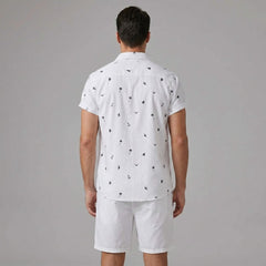 Back view of man wearing white palm tree anchor sailboat print shirt and swim shorts