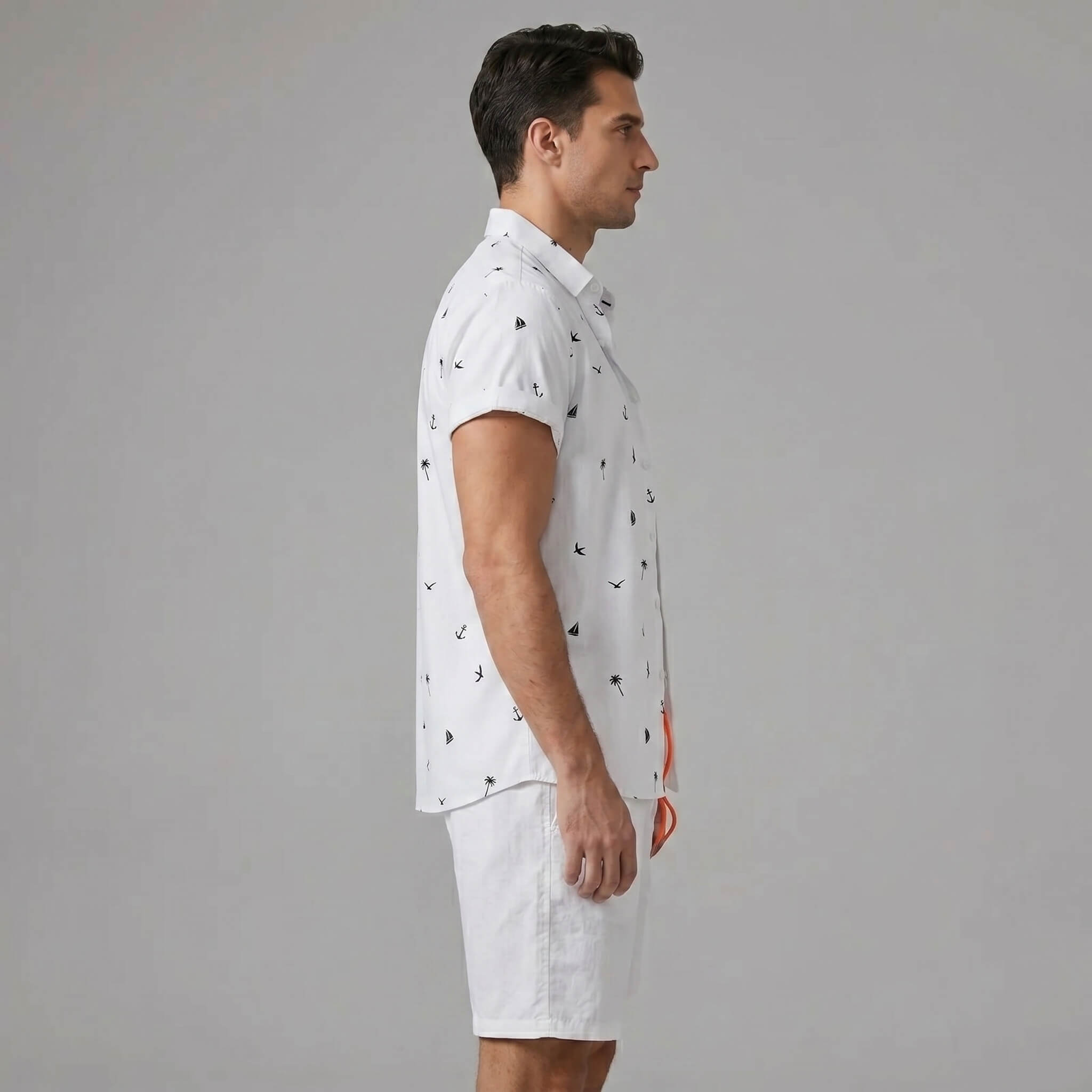 Side view of man in white palm tree anchor sailboat print shirt and swim shorts on plain background