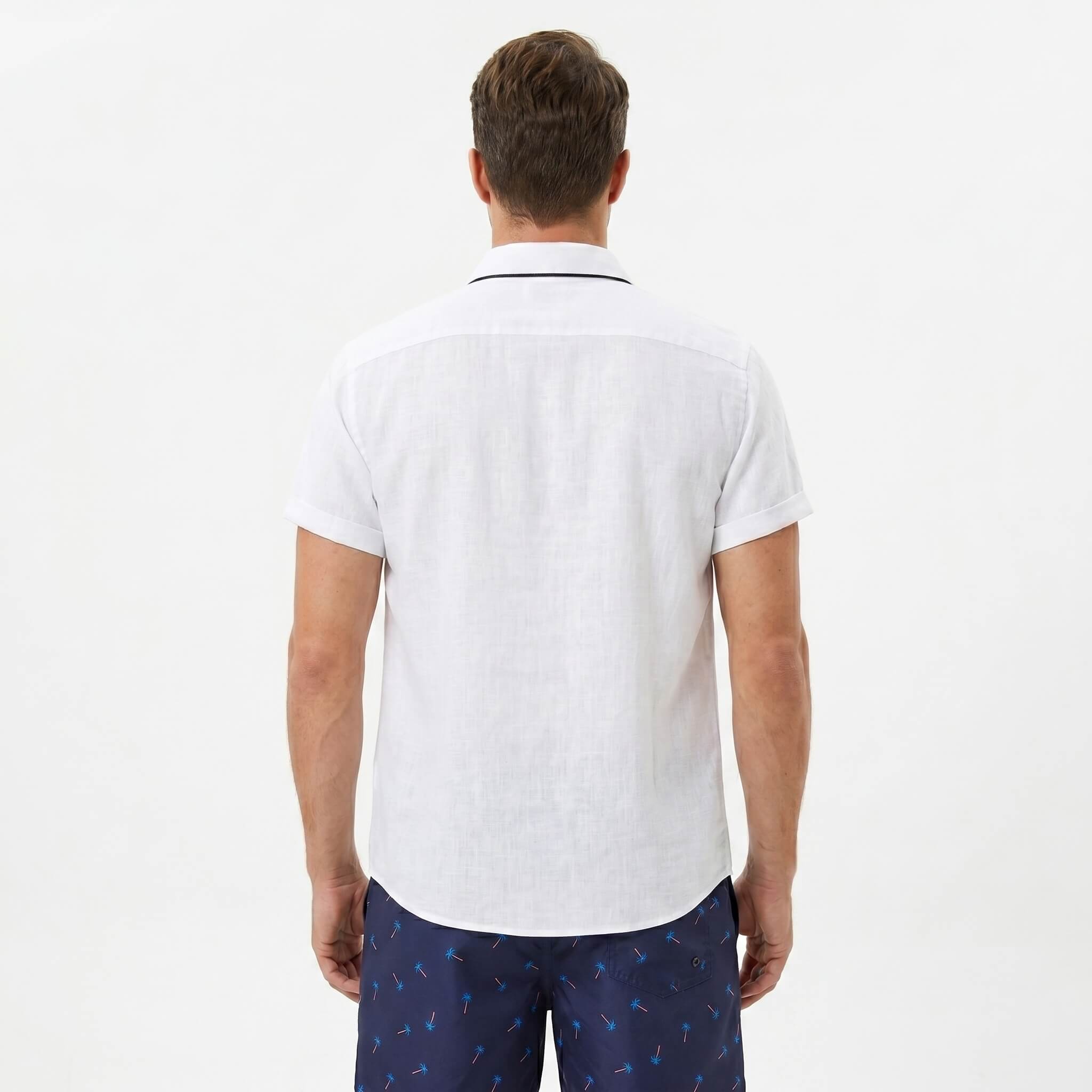 Back view of man wearing white palm tree print linen look cotton shirt and swim shorts