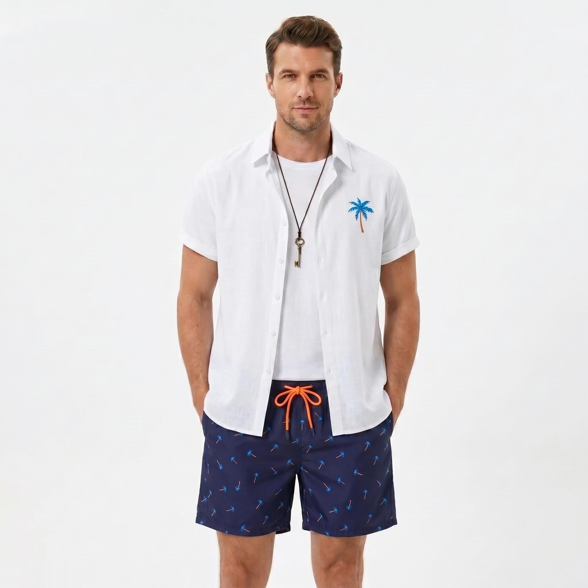 Man wearing a white palm tree print linen look cotton button up shirt and swim shorts front view on plain background