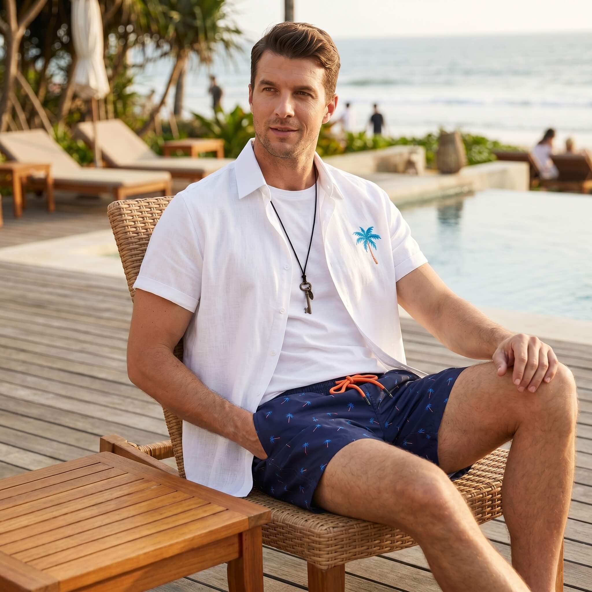 Man in white palm tree print linen look shirt and swim shorts at sunny outdoor resort lifestyle scene